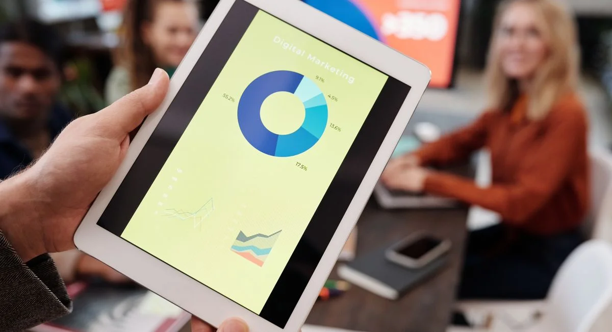 Business team reviewing digital marketing statistics on a tablet during an indoor meeting.